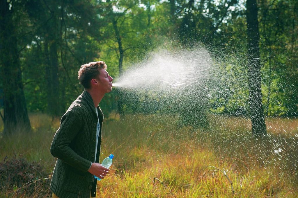 man spitting water on woods